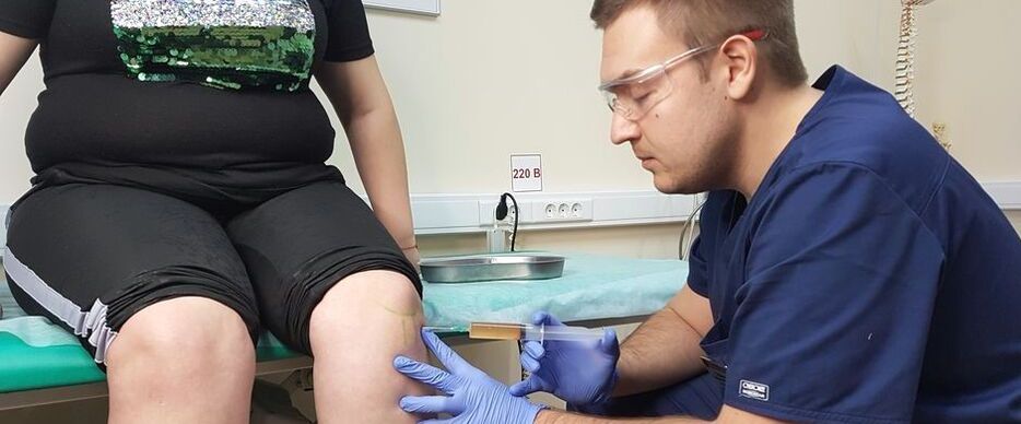 An orthopedic doctor gives an intra-articular injection in the knee joint for osteoarthritis