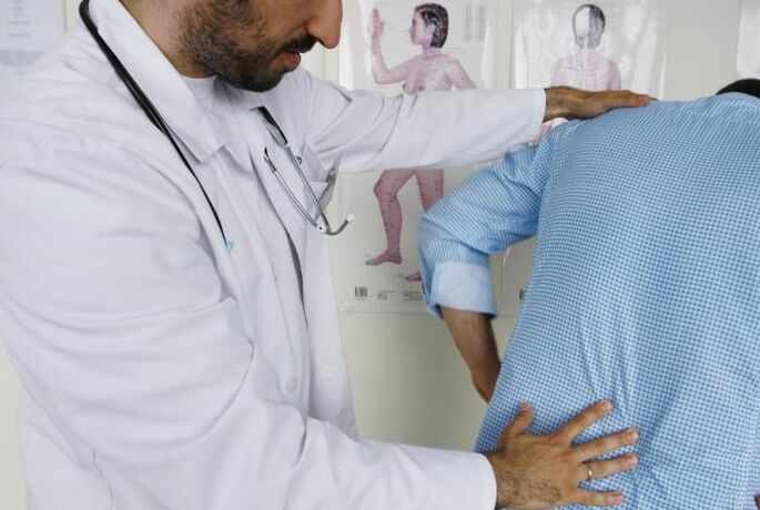A doctor examines a patient with back pain in the lumbar region